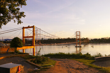 Old Bridge over Ping River mountains as background. Mueang Tak District, Thailand. River landscape....