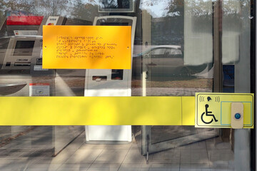 Disabled person sign with braille text and a panel with a button to call staff for assistance at...