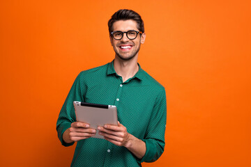 Photo of cool positive guy wear green shirt communicating modern gadget isolated orange color background