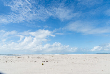 Fototapeta na wymiar White sand on a deserted beach with blue sky and clouds in the background. Preserved environment.