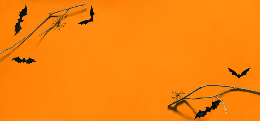 Spooky Halloween Night: Bats, Branches, and Spiders on an Orange Background. Copy space. Banner