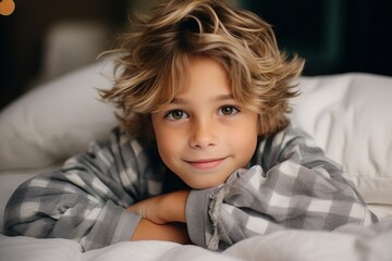 Portrait of a cute little boy in pajamas lying in bed. - obrazy, fototapety, plakaty