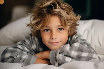 Fotobehang Portrait of a cute little boy in pajamas lying in bed. © Nerea