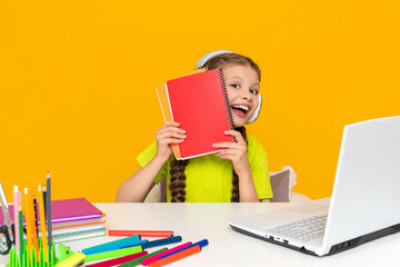 The child does homework on a laptop at home and holds a notebook in his hands. Distance online...