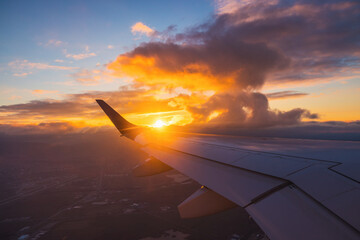 Airplane flight in sunset sky over ocean water and wing of plane. View from the window of the...