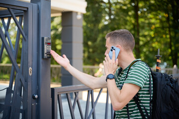 Man opens the gate to yard. Young male calling owner to ask code. Curious tourist trying to open...