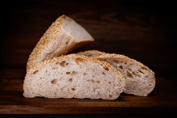 Cut loaf of bread and pieces of bread on a wooden background. Ciabatta bread.
