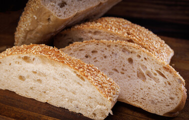 Cut loaf of bread and pieces of bread on a wooden background. Ciabatta bread.