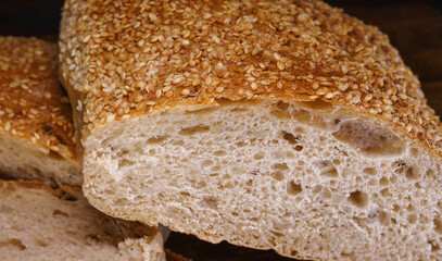 Cut loaf of bread and pieces of bread on a wooden background. Ciabatta bread.