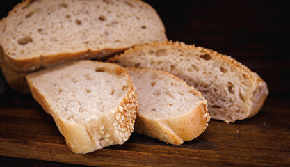 Cut loaf of bread and pieces of bread on a wooden background. Ciabatta bread.