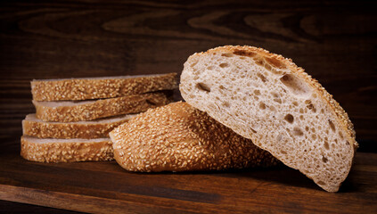 Cut loaf of bread and pieces of bread on a wooden background. Ciabatta bread.