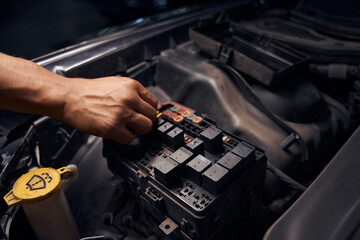 Male auto-mechanic changing relay and checking operation of the fuses