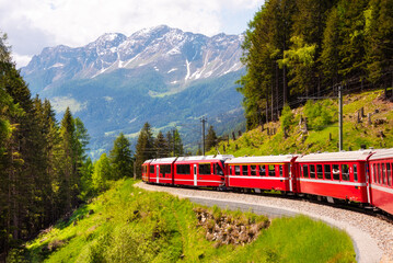 Red train moving in beautiful mountain landscape in Switzerland