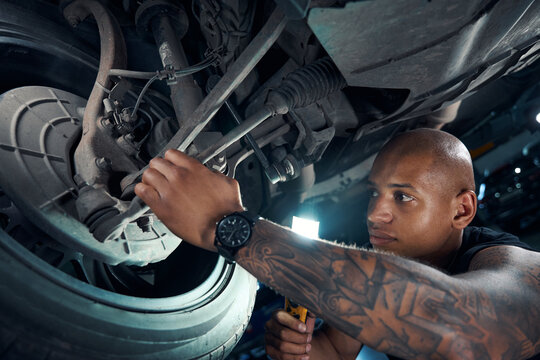 African American car owner checking strength of hub to which wheels are attached