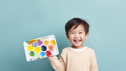 Happy child holding a palette and paintbrush