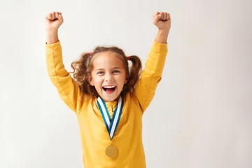 Foto op Canvas Portrait of a happy little girl with medal celebrating victory over white background © Anna