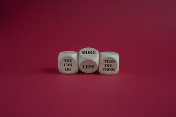 Turned dice and changes the expression you can do less than you think to you can do more than you think. Beautiful red background, copy space. Business, motivational concept.