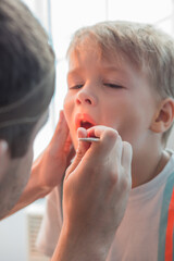 A child with ears pain at the hospital. Doctor otolaryngologist checking child ears in the...