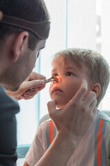 A child with nose pain at the hospital. Doctor otolaryngologist checking child ears in the hospital. Cute boy with bad ears at the doctor's office in the clinic.