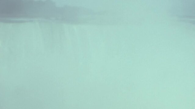 Niagara WaterFalls panoramic view from right to left from the point where the water falls, with cloud of spray obscuring the view. Side view. Vintage 1970s stock footage with super 8mm video effect. 