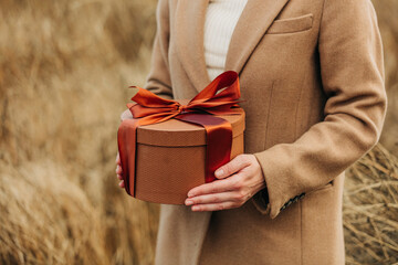 Hands of woman holding gift box in field
