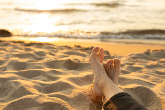 Woman with barefeet relaxing on sand at beach