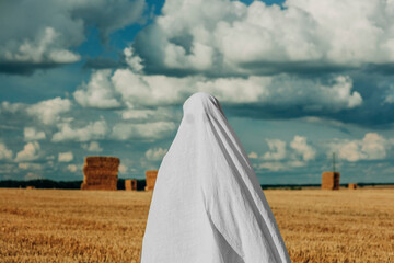 Woman wearing ghost costume standing in wheat field