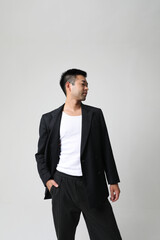 Portrait of smiling young Asian businessman in black suit isolated indoor. 