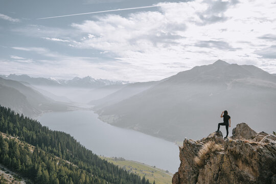 Wundersch&ouml;ner Ausblick auf den Reschensee. 2000 Meter hoher Aussichtspunkt im Vinschgau. Frau steht an einer Felskante. See