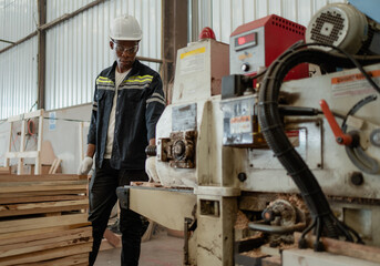 Skilled multiracial worker standing in lumber warehouse of hardwood furniture factory using wood...