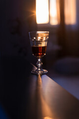 Glass with ruby beer on the table at sunset