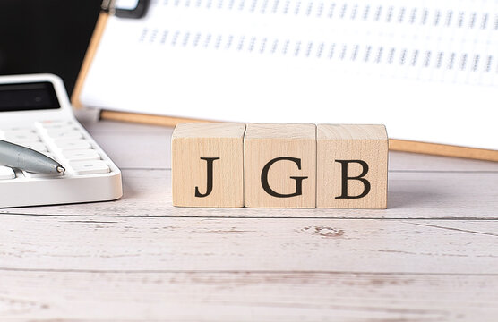 JGB word on a wooden block with clipboard and calcuator
