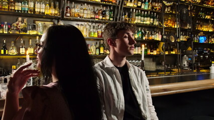 Sad drunk man sits on bar stool and puts shot glass on table. Young guy tries to relieve anxiety and torments with alcohol