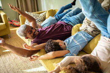 Young father playing and having fun with his children on the couch at home