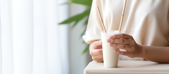 Asian woman drinks pearl milk tea using eco friendly bamboo straw in restaurant to reduce plastic waste