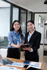Smiling young Asian woman talk with female colleagues brainstorm at office team meeting. Teamwork collaboration concept.