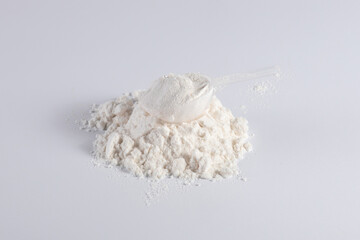 Protein with plastic measuring spoon on white background