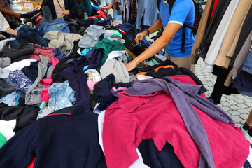 person looking for used clothes for sale in the flea and used clothing market - obrazy, fototapety, plakaty