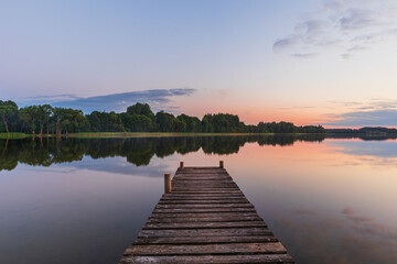 A beautiful natural view of the lake from the wooden footbridge on a summer evening during the sunset