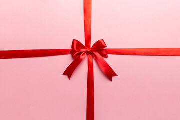 Top view of Red ribbon rolled and red bow isolated on colored background. Flat lay with copy space