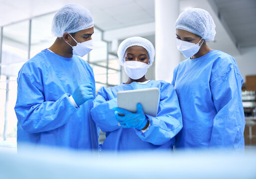 Doctor, Tablet And Meeting With Mask In Planning Or Collaboration For Surgery Ideas At Hospital. Group Of Medical Employees With Technology In Teamwork, Consulting Or Healthcare Strategy At Clinic