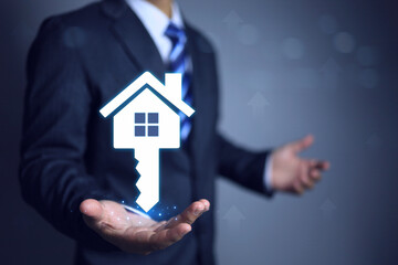 Businessman hold house key in hand, investment and stability in real estate and the reliability of building house with engineering work, giving resident confidence in the quality house.