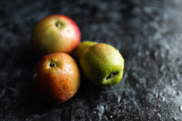 Apples, pears, green and purple grapes lie on a dark background. Organic fruit close-up. Fruits on a black background. Wet washed fruits on a black marble table