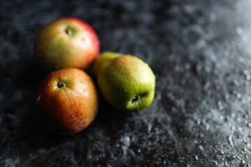 Apples, pears, green and purple grapes lie on a dark background. Organic fruit close-up. Fruits on a black background. Wet washed fruits on a black marble table