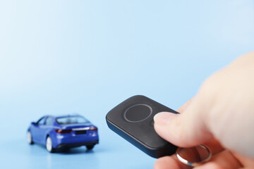 theft protection, car alarm, security remote control in hand against the background of a car