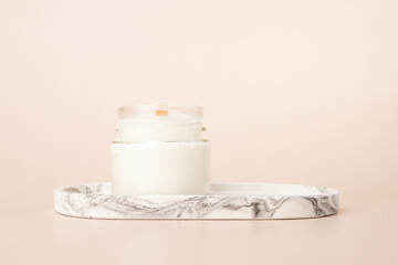 Fototapeta na wymiar Candle on a marble stand on a beige background, coconut wax, Spa Relaxation