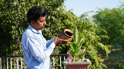 Hindu devotee offering water or Ardhya to the sun God at home on terrace.