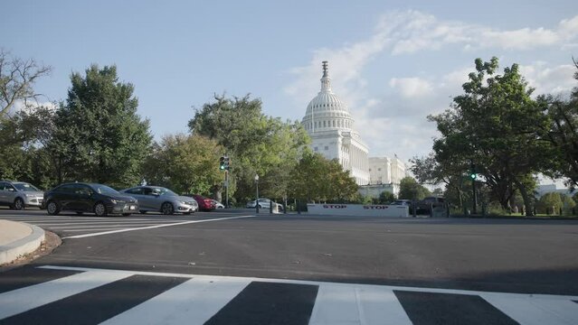 Slow motion view of Capital building holding congress house representatives and senators in Washington DC, including pedestrians, streets, and traffic during a bright, fall afternoon