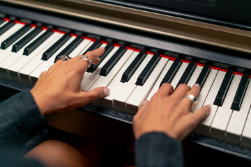 Close-up of a woman's hands in silver rings playing beautiful lyrical melody on the piano keys 
