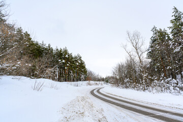 Snowy winter road in a mountain forest.
